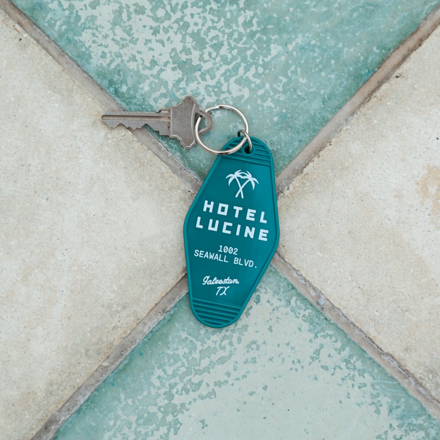 Blue keychain with 'Hotel Lucine' branding on a textured surface