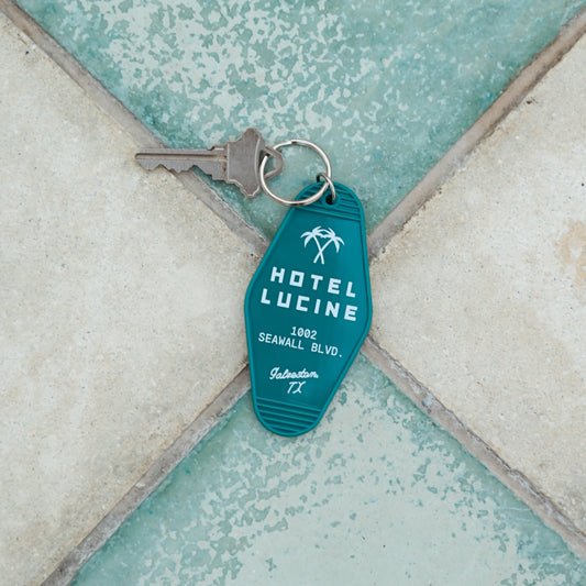 Blue keychain with 'Hotel Lucine' branding on a textured surface
