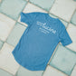 Blue t-shirt with 'Hotel Lucine' text on a tiled floor